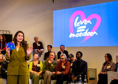 Presentator Nadia Moussaid met op de achtergrond het Leven=Meedoen logo.